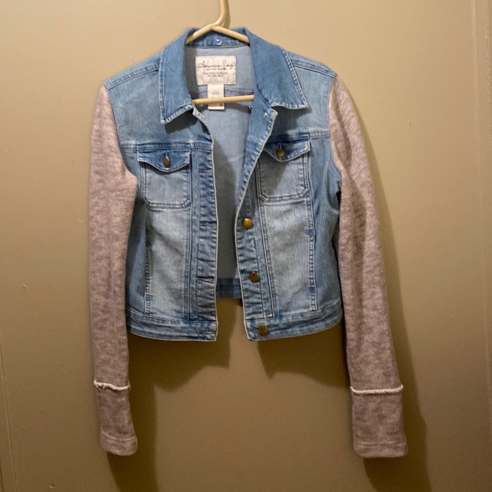 American Rag small cropped denim jacket with gray knit sweater sleeves.